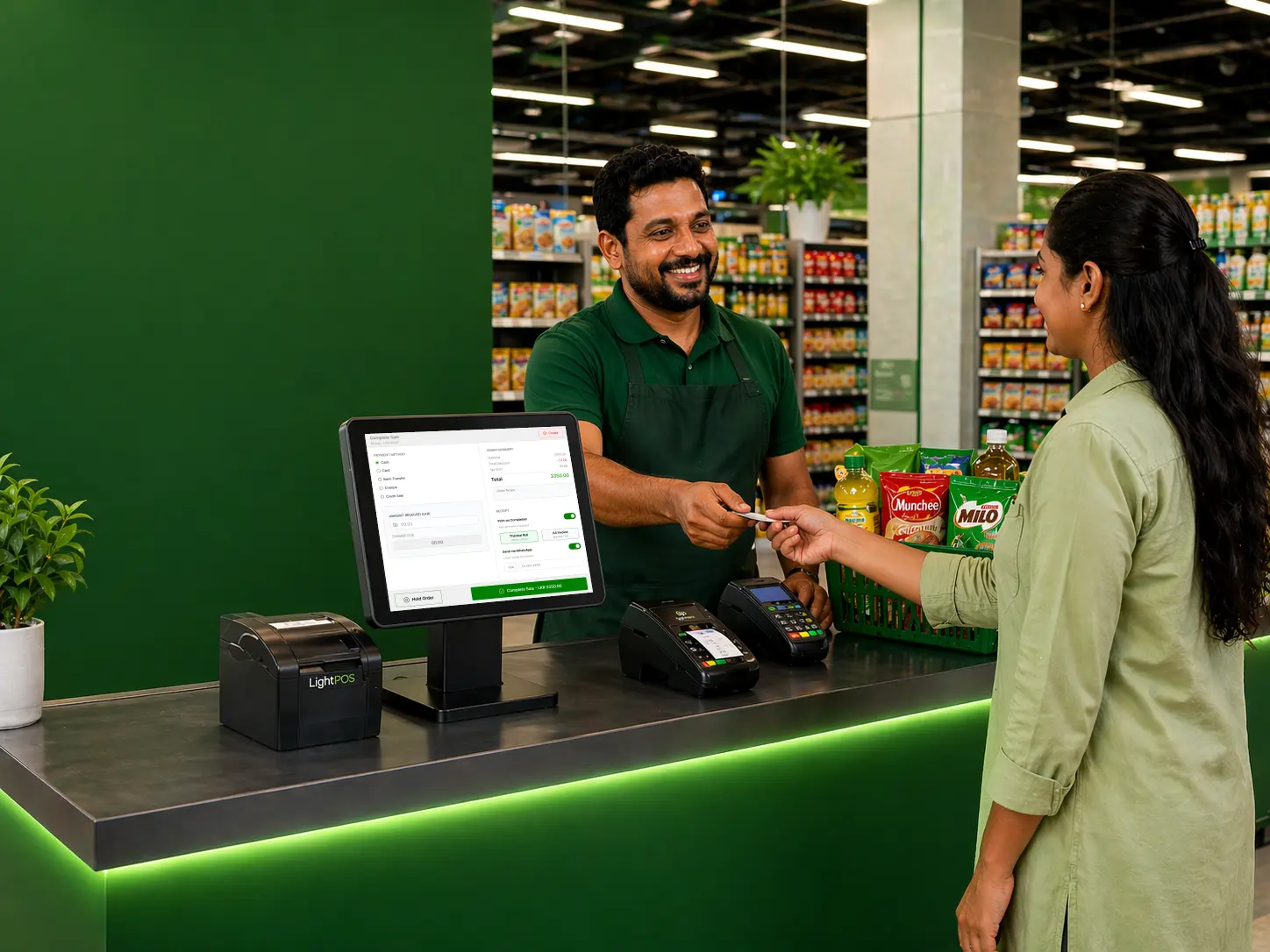 A Sri Lankan shop owner using LightPOS on a tablet at the counter to process a customer's payment, with shelved products visible in the background